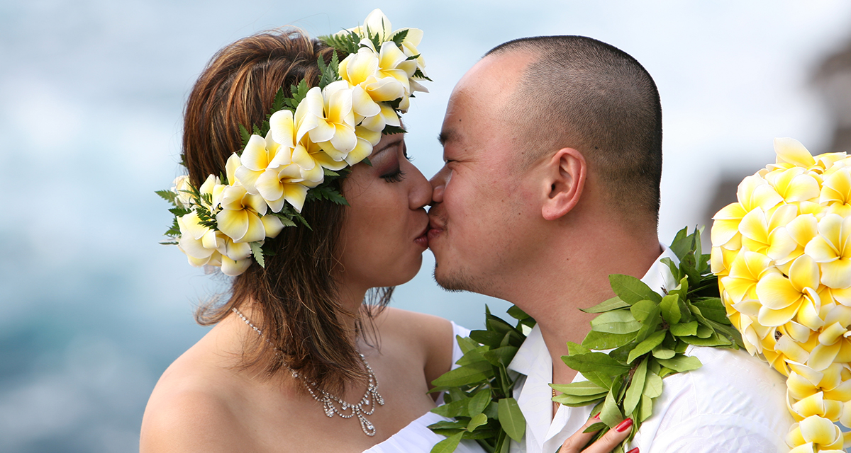 kissing her husband with a yellow plumeria haku lei